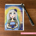 Illustrated card with a character on a wooden surface with a pen next to it.