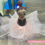 A handcrafted wooden ballerina doll with brown hair in a bun, a black dress, and a fluffy white tulle tutu, displayed on a wooden surface.