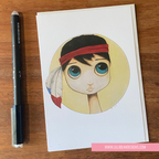 Illustration of a character with a red headband on a card, next to a pen on a wooden surface.