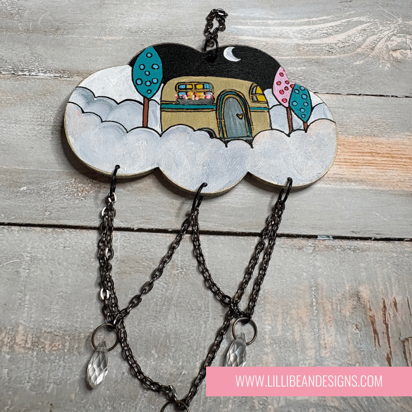 Decorative cloud-shaped hook with a small house illustration on a wooden surface, featuring the brand 'LilliBean Designs'.
