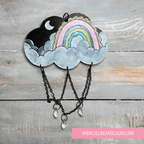 Decorative cloud-shaped hooks with illustrations on a wooden surface, labeled with rainbow image. LilliBean Designs