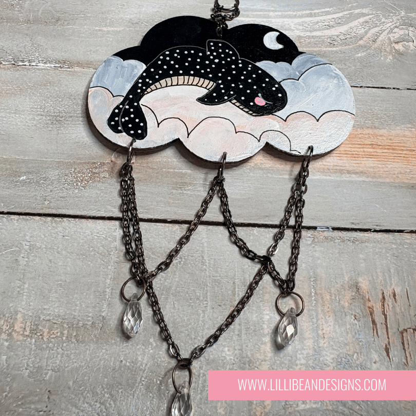 Decorative cloud-shaped hooks with illustrations on a wooden surface, labeled with whale shark image. LilliBean Designs