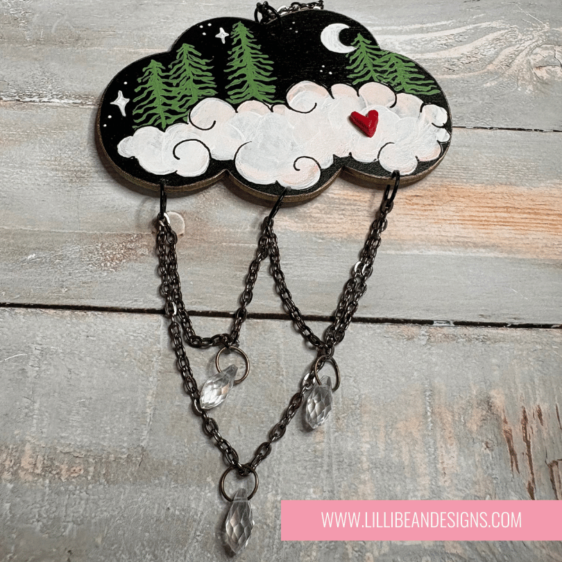 Decorative cloud-shaped wall hanging with chains and heart on a wooden surface, featuring LilliBean Designs branding.