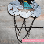 Decorative cloud-shaped hooks with illustrations on a wooden surface, labeled with sailing boat image. LilliBean Designs