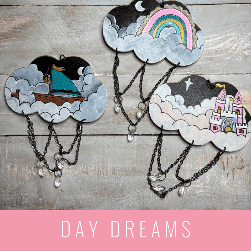 Decorative cloud-shaped hooks with illustrations on a wooden surface, labeled 'Day Dreams'. LilliBean Designs