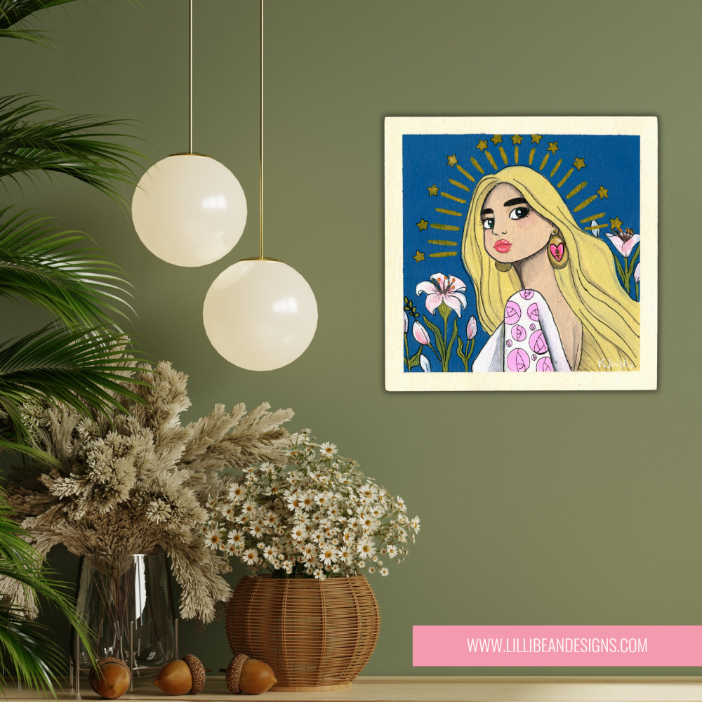 Framed artwork of a woman with flowers on a wall with decorative plants and lights.