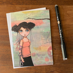 GREETING CARD with an illustration of a girl on a wooden surface with a pen next to it