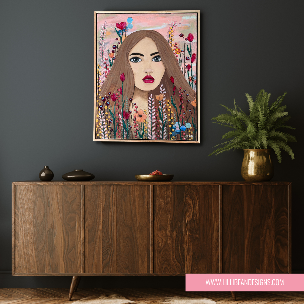 Artistic depiction of a woman's face surrounded by flowers on a dark wall above a wooden cabinet.