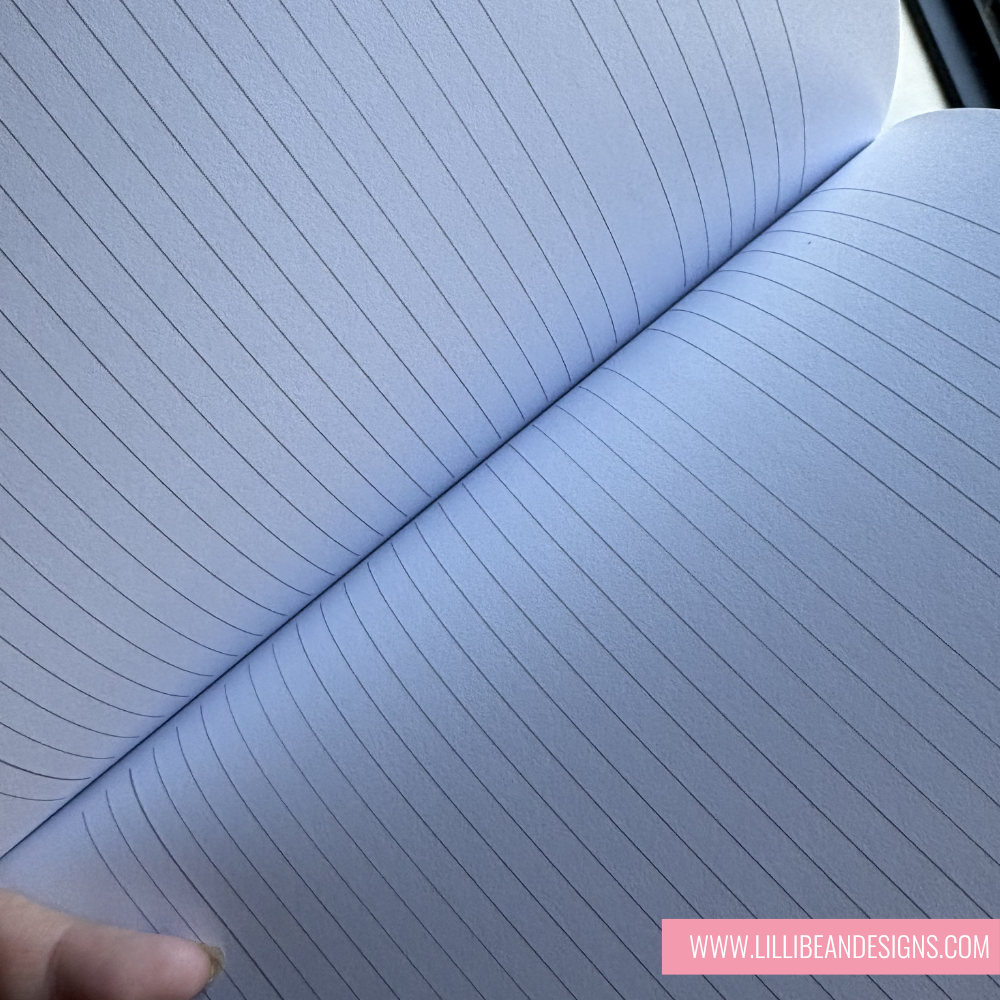 Close-up of a notebook with lined pages, held by a hand.