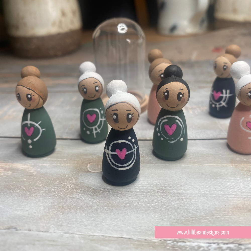Set of wooden peg dolls with different hairstyles and outfits on a wooden surface.