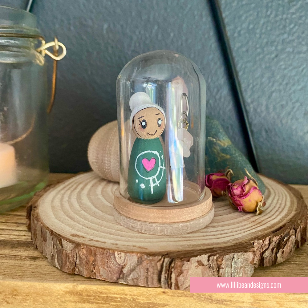 Small figurine under a glass dome on a wooden base with a blurred background