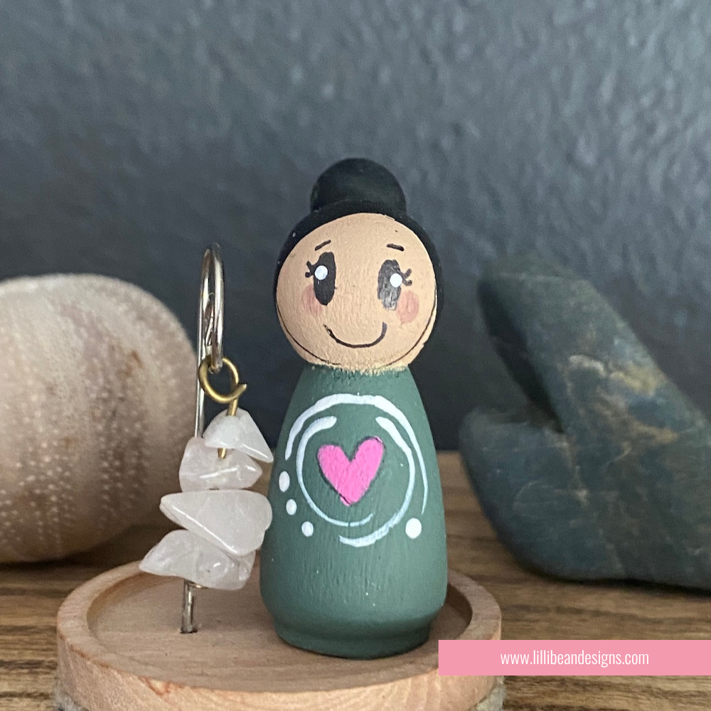 Small figurine with a pink heart design on a wooden stand with a dark background