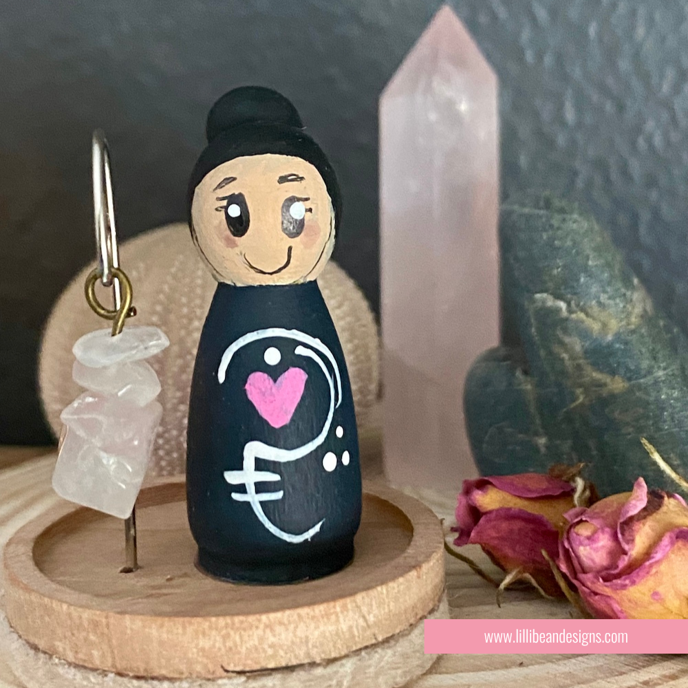 Peg doll with a heart and euro symbol on a wooden stand with a dark background