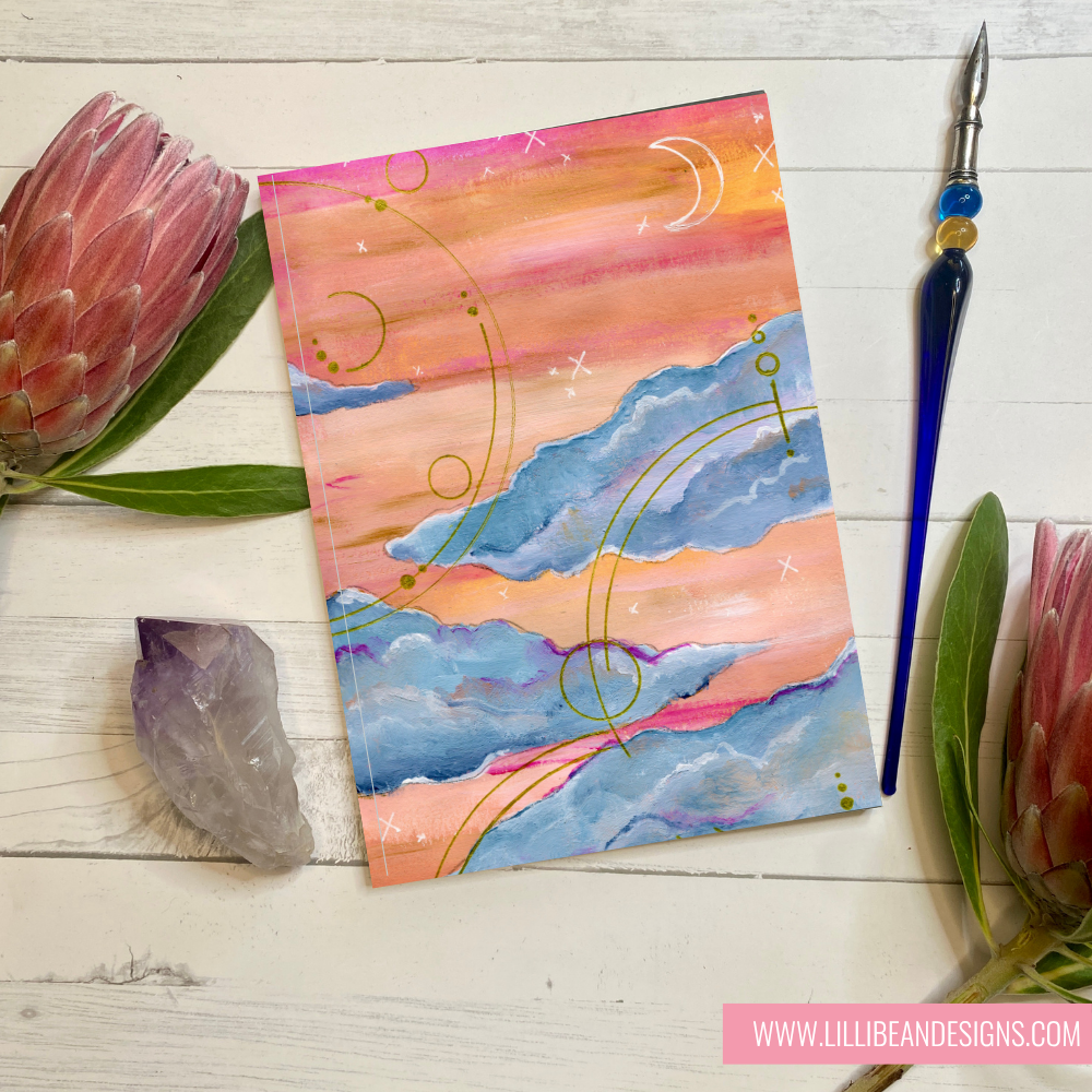 Colorful abstract painting on a wooden surface with natural elements and a pen.