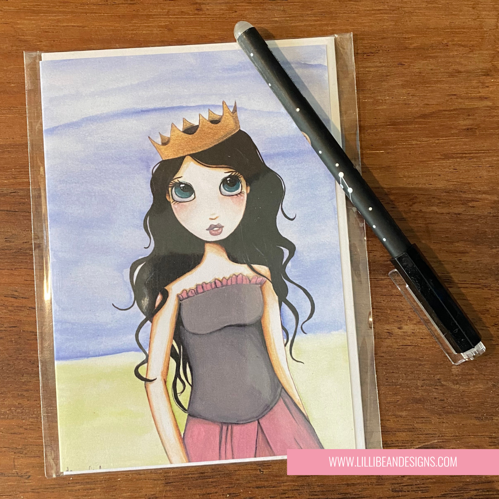 Illustrated card of a princess with a crown and a pen on a wooden surface