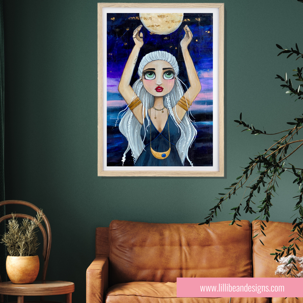 Framed artwork of a woman holding the moon above her head in a room with a brown leather couch and plant.
