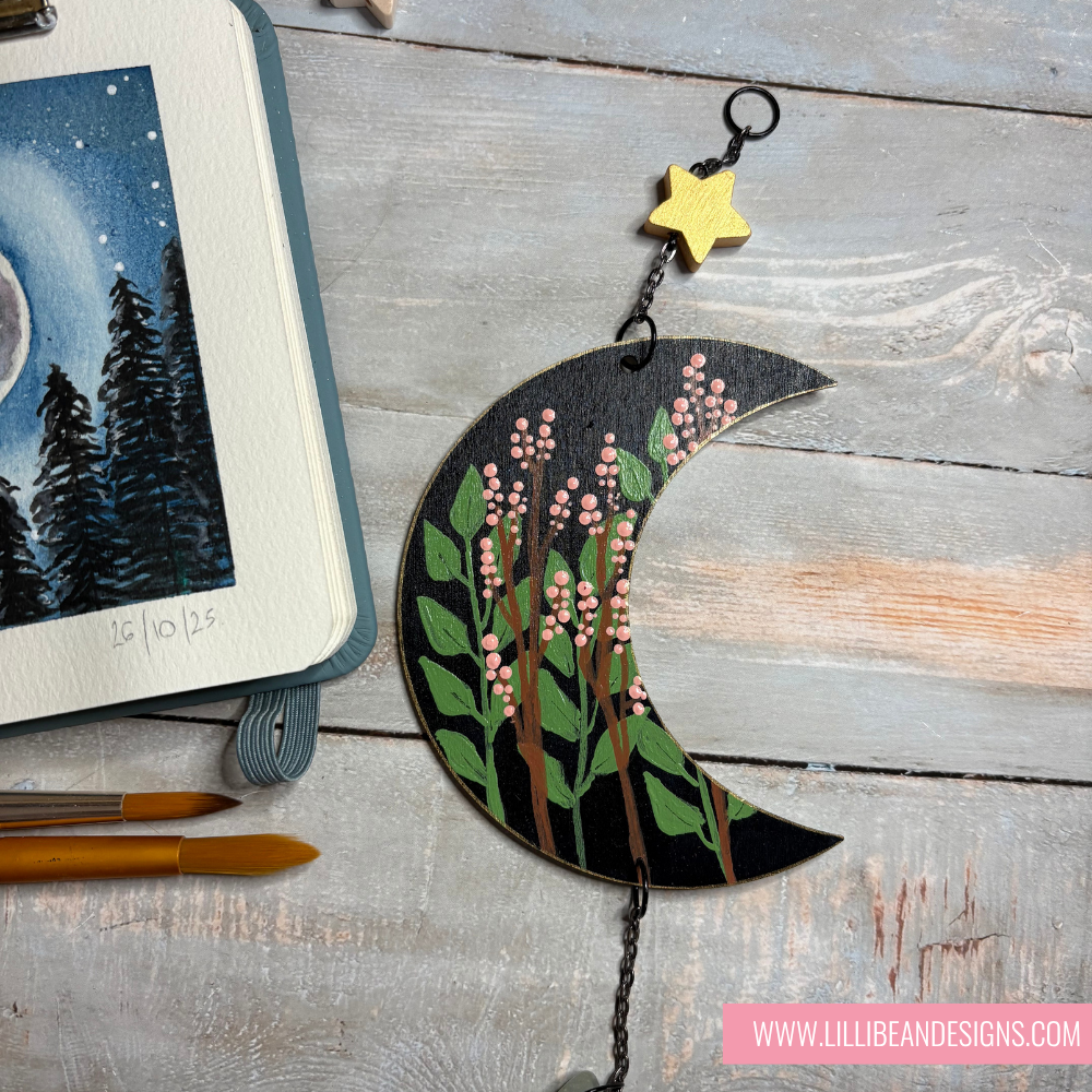 Decorative moon-shaped ornament with floral design on a wooden surface, featuring LillieBean Designs branding.