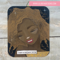 Artistic depiction of a woman's face with 'I am a radiant being' text, on a wooden surface.