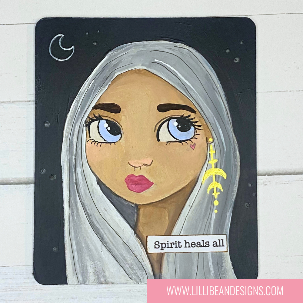 Illustration of a woman with white hair and blue eyes, wearing a yellow earring, on a black background with text 'Spirit heals all'.