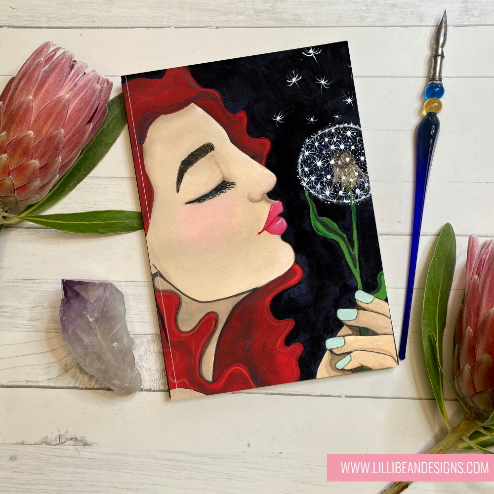 Artistic depiction of a woman with flowers on a wooden surface, featuring Lillie Be Designs branding.