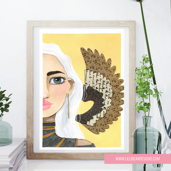 Framed artwork of a woman with a decorative angel wing on a yellow background, displayed on a shelf.