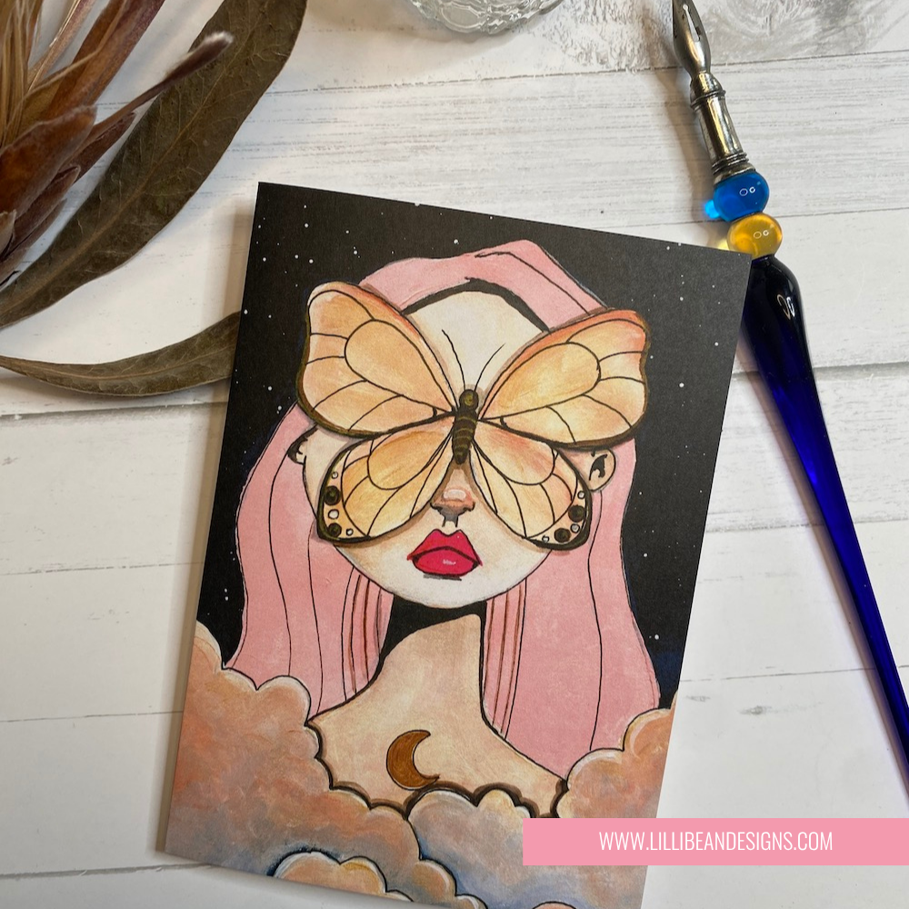 Illustration of a person with a butterfly on their face, surrounded by clouds and a starry sky, with LillieBean Designs branding. GREETING CARD