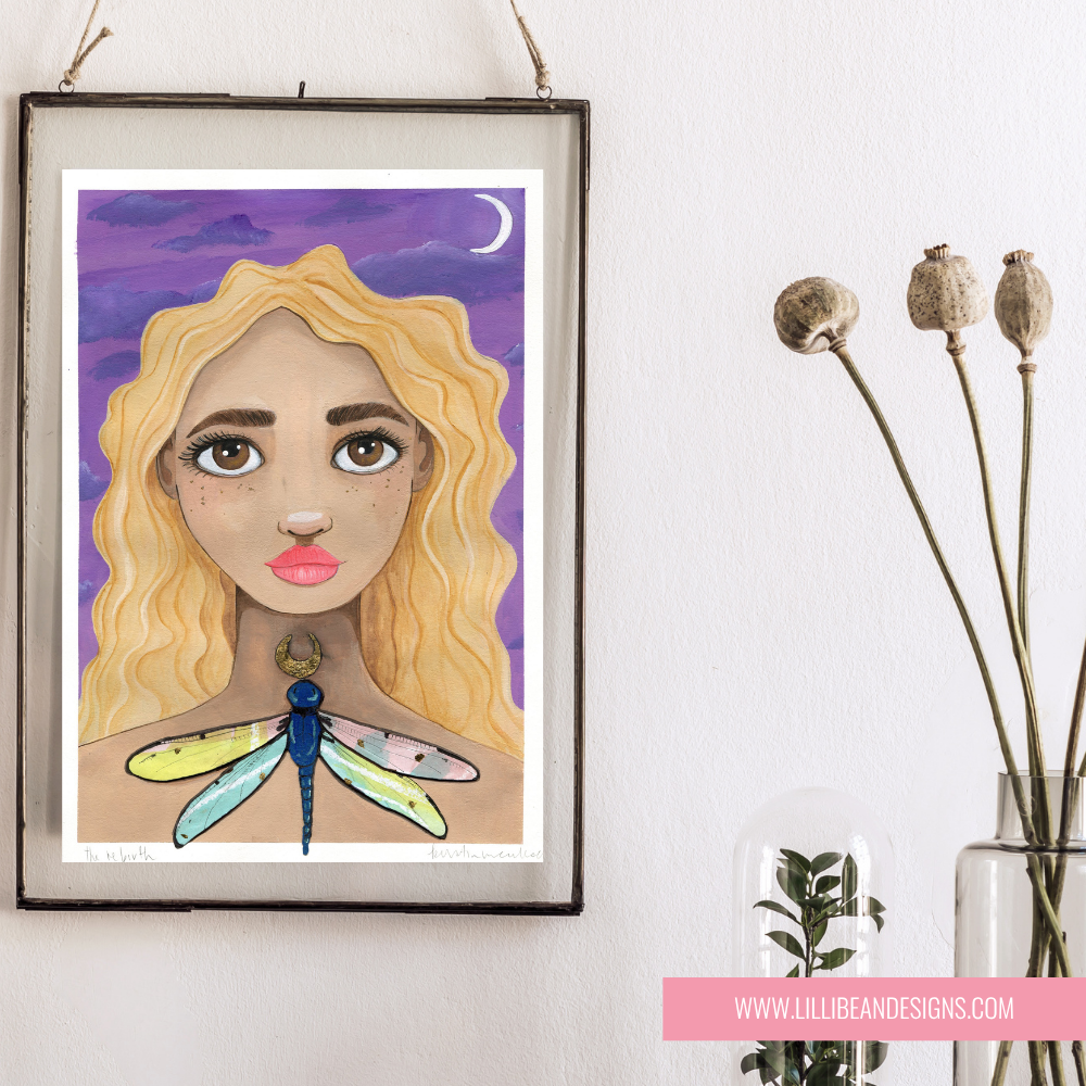 Framed artwork of a woman with a dragonfly on her chest, hanging on a wall.