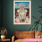 A framed art print featuring a whimsical illustration of a woman with white hair in a cream dress, surrounded by colorful butterflies in a field, displayed on a dark green wall above a brown leather sofa.