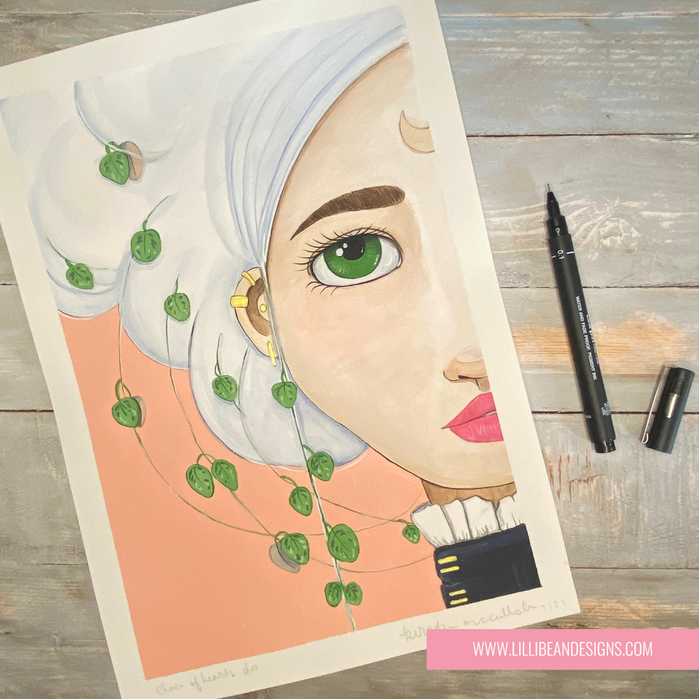 A flat-lay photograph of an art print featuring a stylized portrait of a woman with white hair, green eyes, and pink lips, decorated with green ivy vines. The print is displayed on a rustic gray wooden table alongside a black marker and a black pen cap, with a pink brand label at the bottom right reading 'WWW.