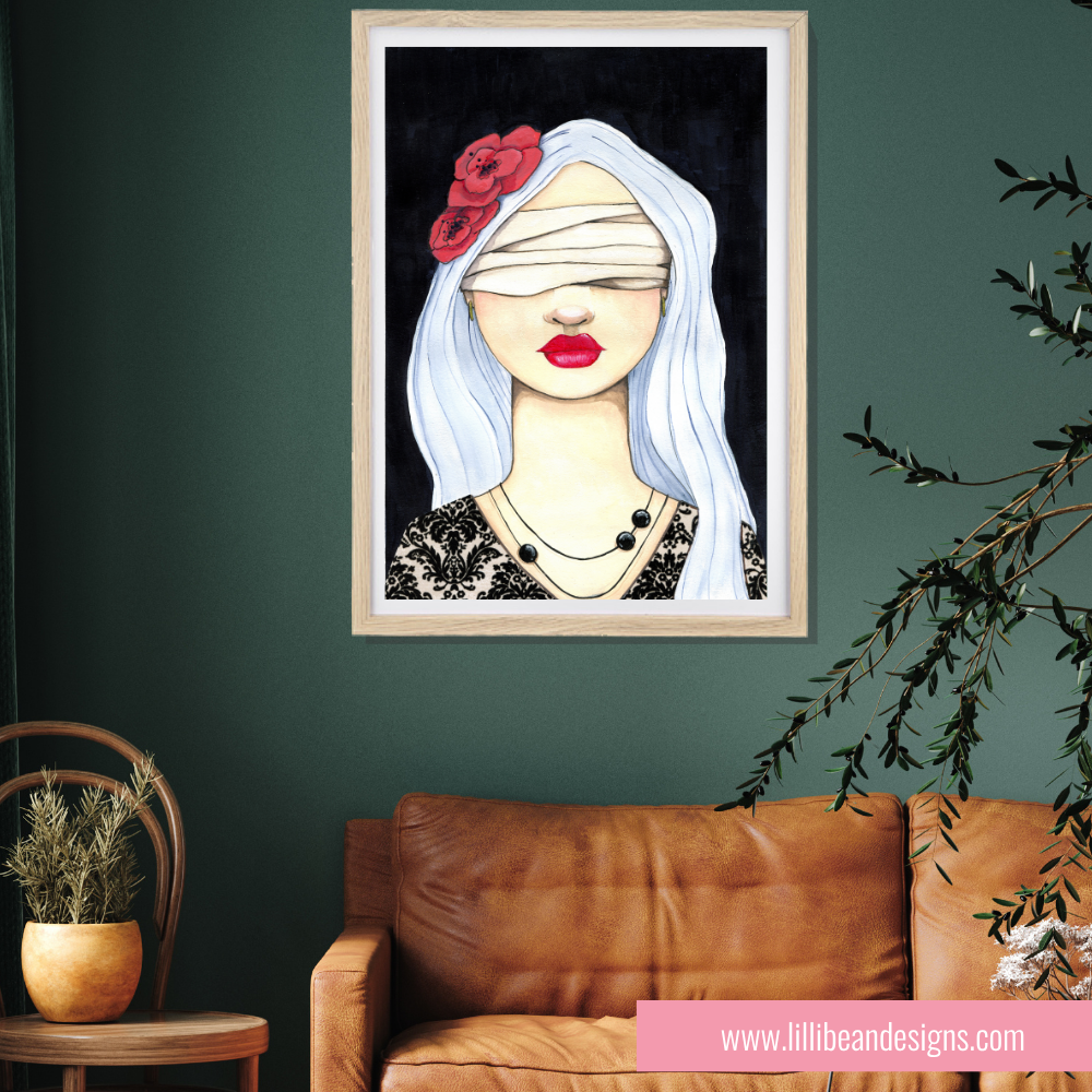 A framed art print featuring a stylized illustration of a blindfolded woman with white hair and red roses, displayed on a dark green wall above a brown leather sofa in a styled living room setting.