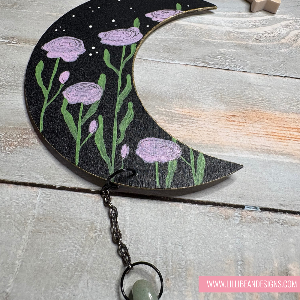 Decorative moon-shaped piece with floral design on a wooden surface, featuring LilliBean Designs branding.