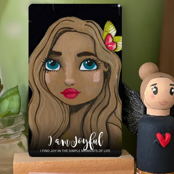 Card with a stylized illustration of a woman's face and text 'I am joyful' next to a small figurine.