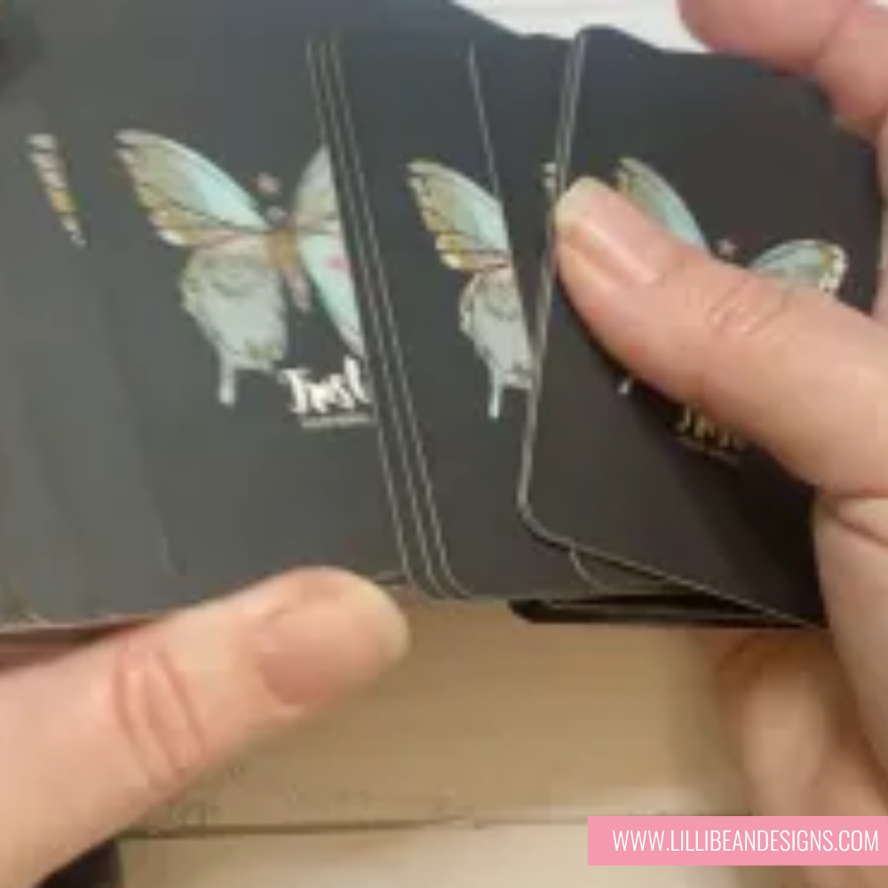 Hand holding a deck of cards with butterfly designs, brand 'LilliBean Designs' visible.