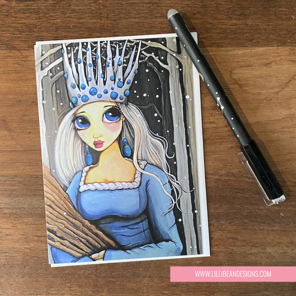Illustration of a princess with a blue dress and crown on GREETING CARD ON a wooden surface with a pen.