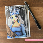Illustration of a princess with a blue dress and crown on GREETING CARD ON a wooden surface with a pen.