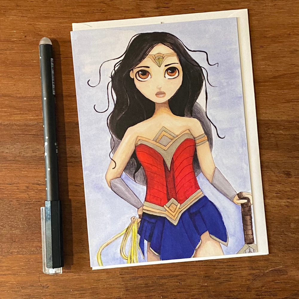Illustration of Wonder Woman on a card with a pen next to it on a wooden surface
