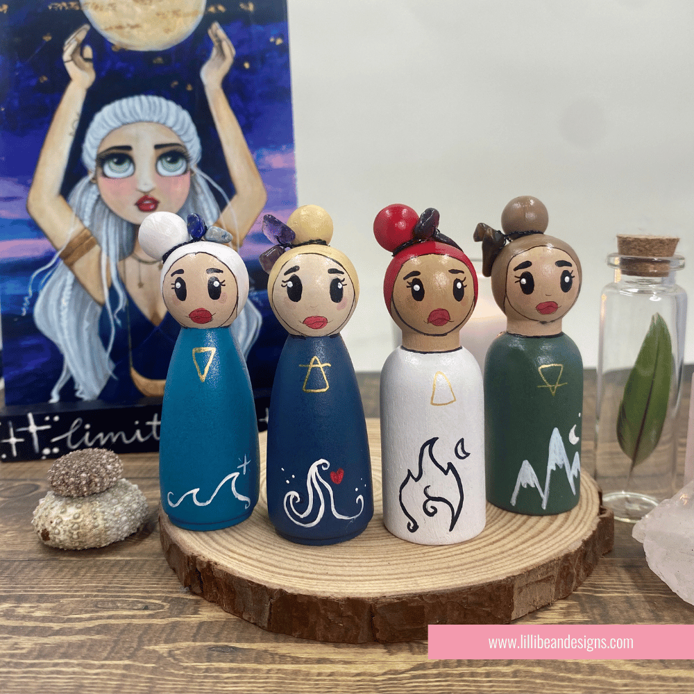 Set of four wooden peg dolls with unique designs on a wooden stand, with a painting and small bottle in the background.