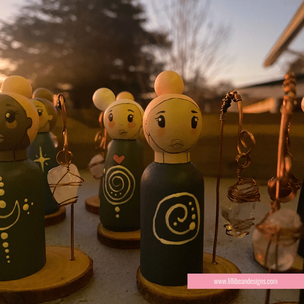 Set of decorative peg dolls with earrings on a blurred outdoor background