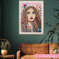 Framed artwork of a woman's face surrounded by flowers on a green wall above a brown sofa.