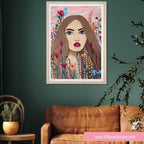 Framed artwork of a woman's face surrounded by flowers on a green wall above a brown sofa.
