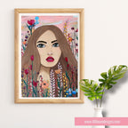 Framed artwork of a woman's face surrounded by flowers on a white wall.