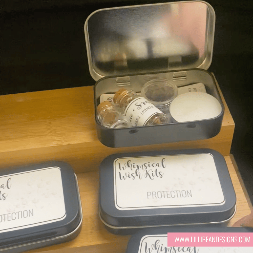 Small tin containers with labeled items on a wooden surface, featuring 'Whimsical Wish Kits' branding.