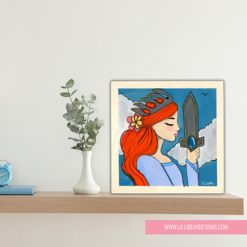 Framed artwork of a woman with red hair holding a sword on a shelf with decor items.