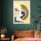 Framed artwork of a stylized portrait on a green wall with a brown leather sofa and plant.