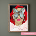 Framed artwork of a woman with red hair and a butterfly on her face against a dark background.