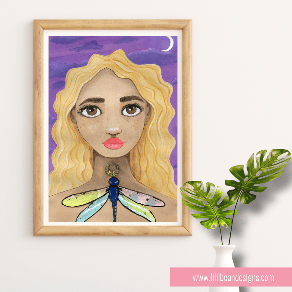 Framed artwork of a woman with blonde hair and a dragonfly on a purple background, displayed on a white wall with a plant.