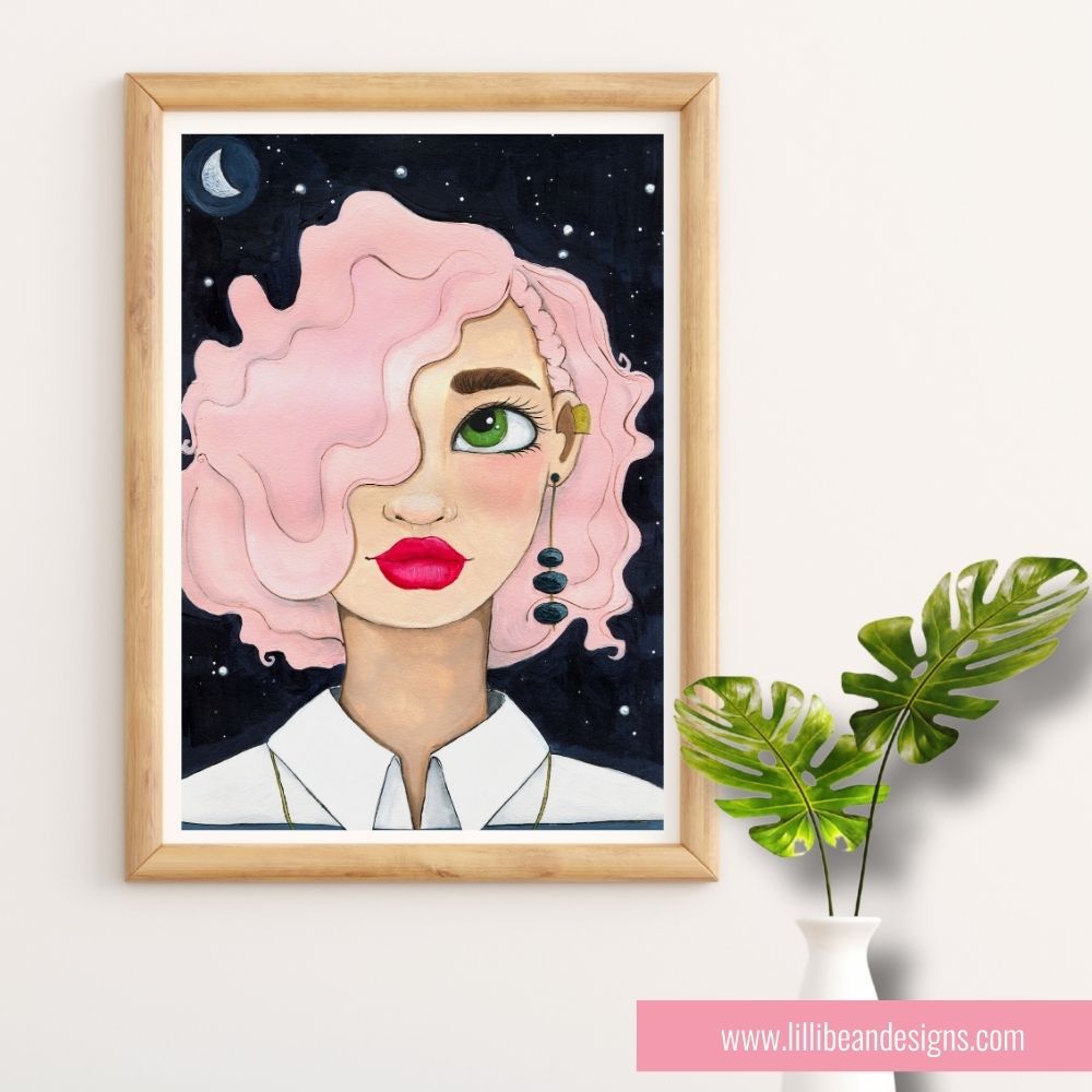 Framed artwork of a woman with pink hair against a night sky, displayed on a white wall with a plant.