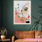 Framed artwork of a stylized face with green leaves on a dark green wall above a brown sofa.