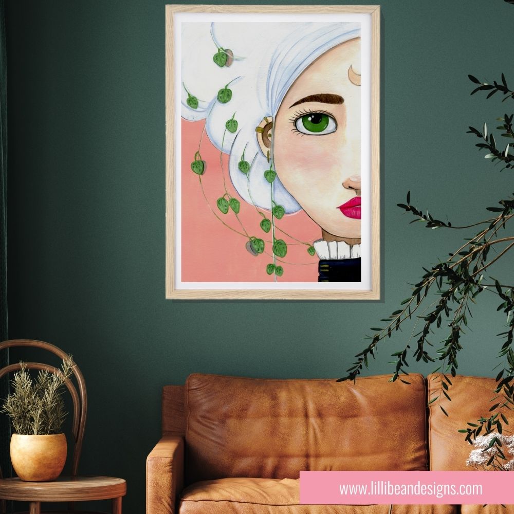 Framed artwork of a stylized face with green leaves on a dark green wall above a brown sofa.