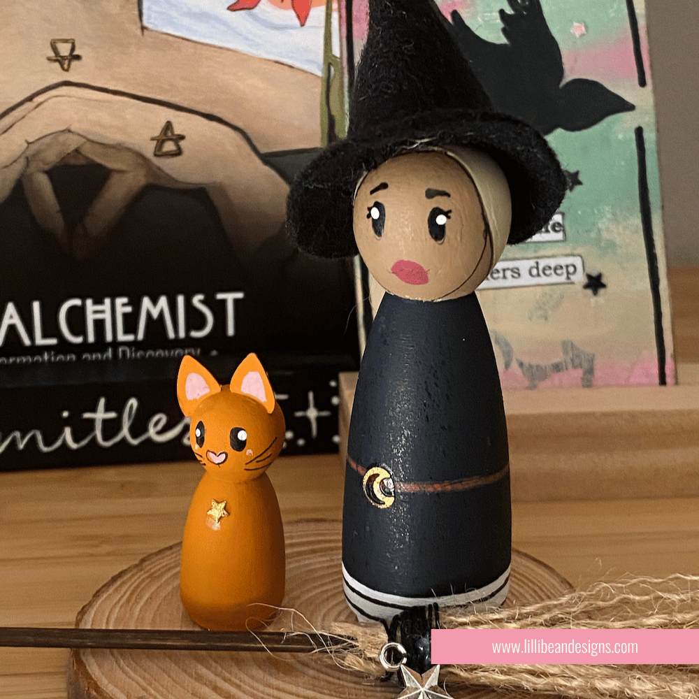 Wooden peg doll of a witch and a cat with a blurred background